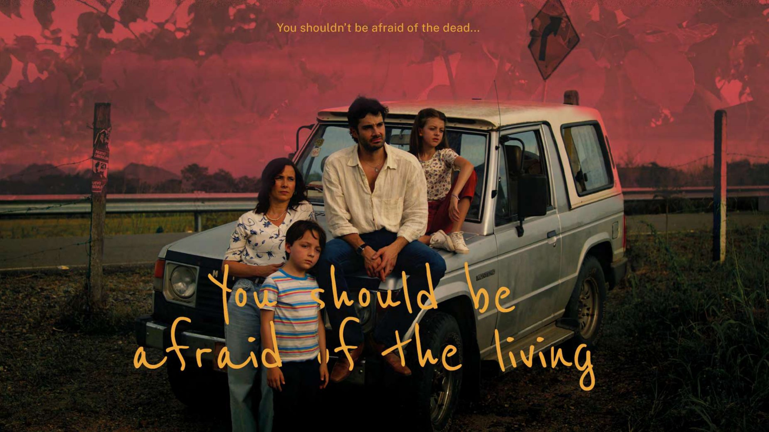 A family gathered beside their car under a red Colombian sky
