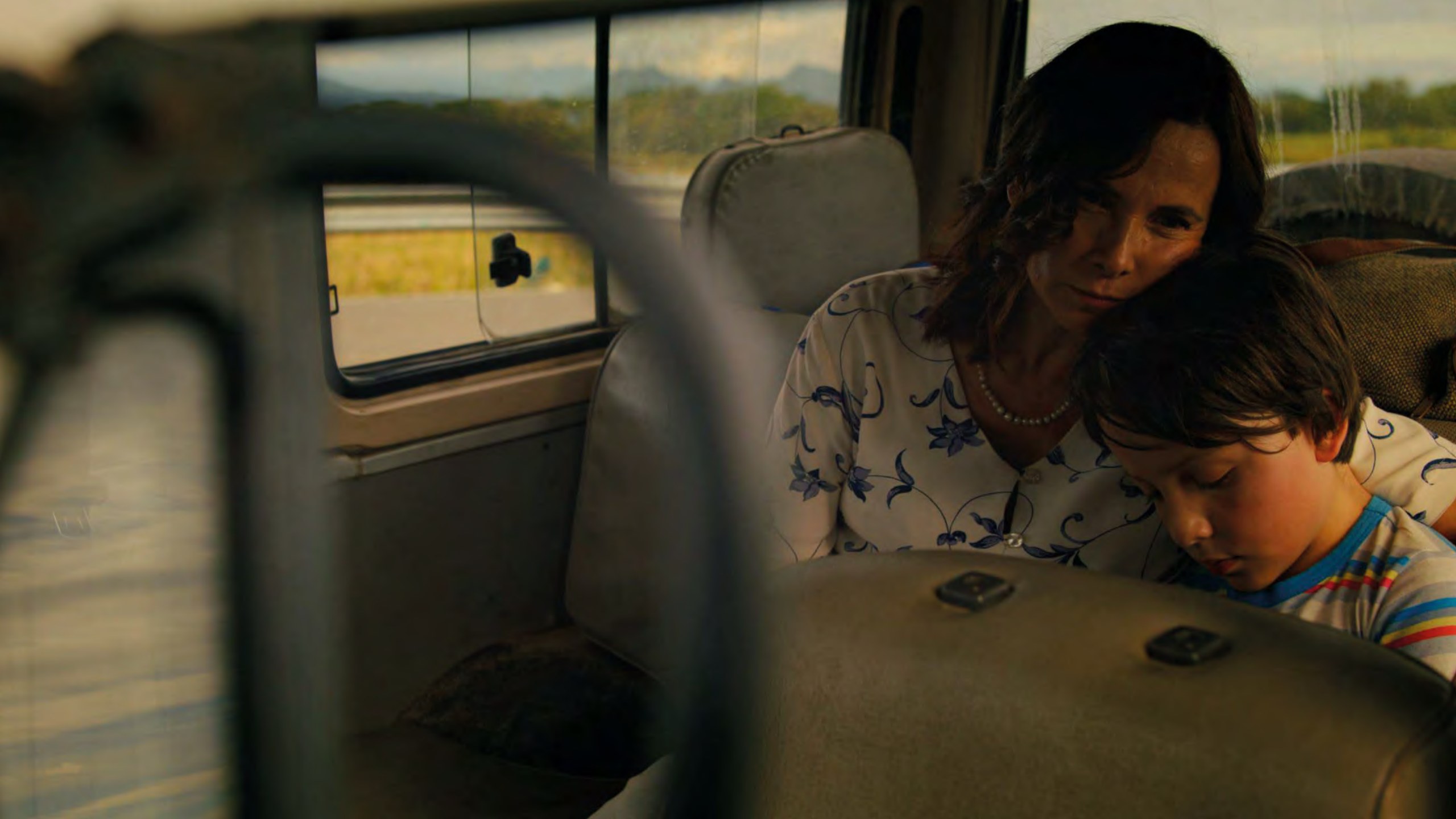 A mother holding her son in the back seat of a car